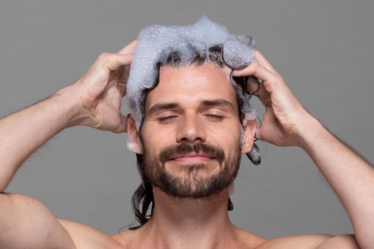 A man applying a dropper full of solution onto his head