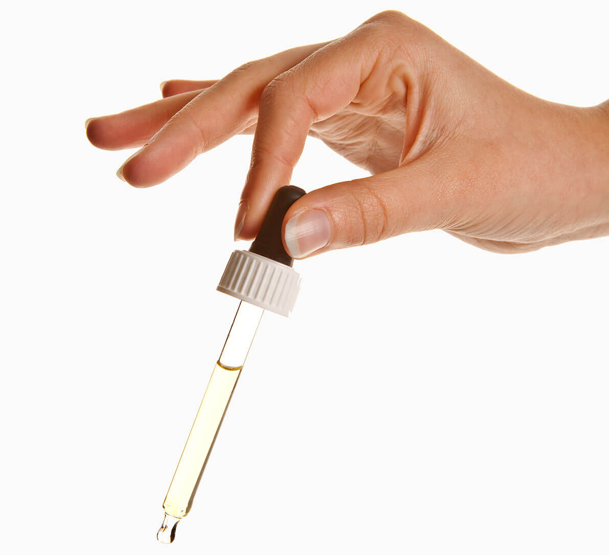 A hand holding a dropper containing pale yellow fluid