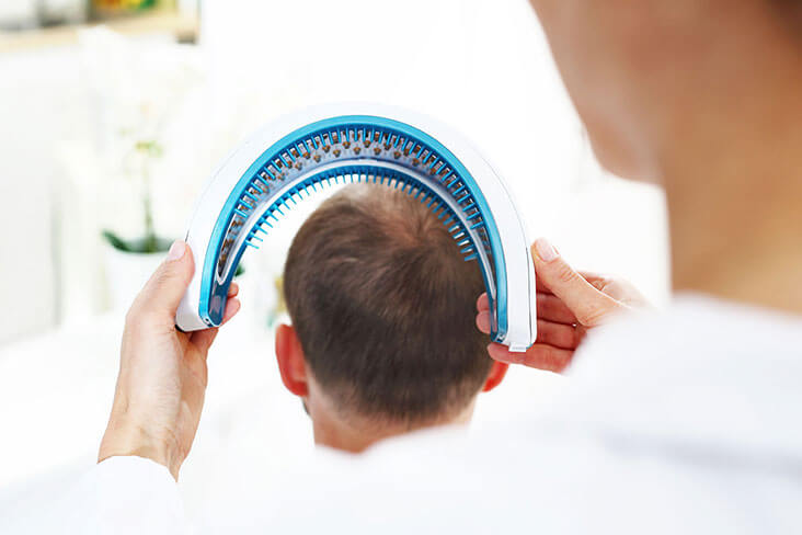 A man applying a dropper full of solution onto his head