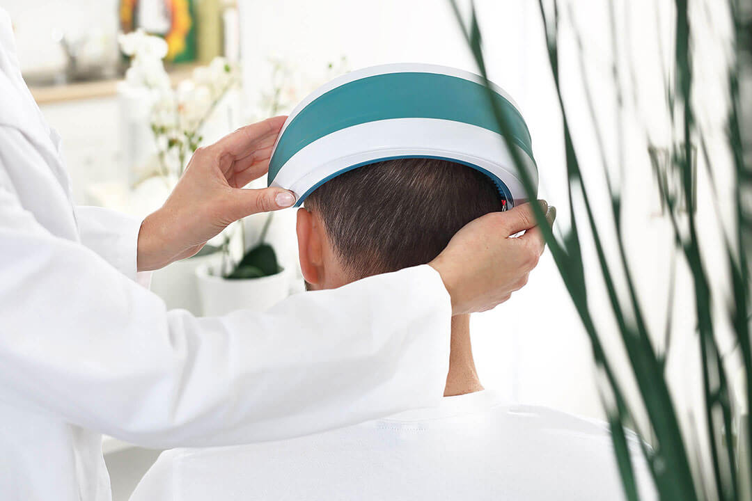 a medical practitioner holding a low-level laser therapy headband to a man's head