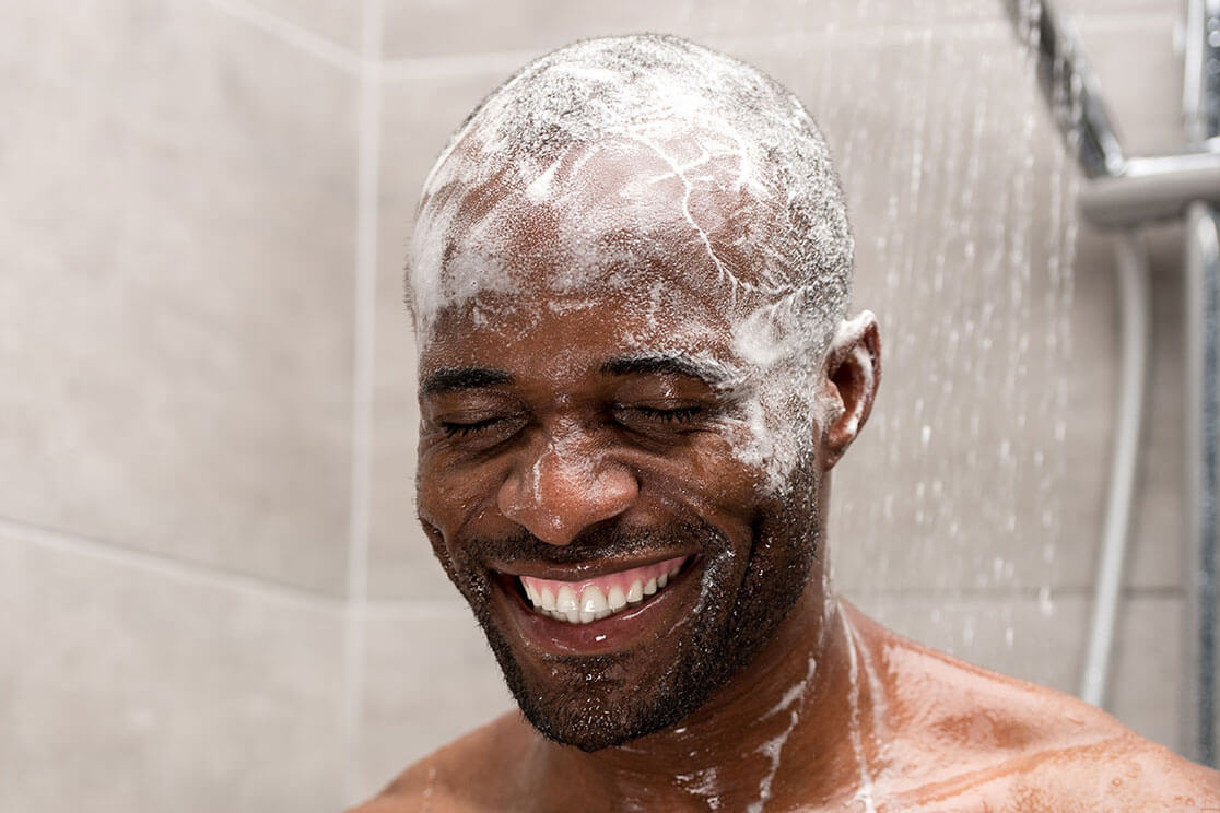 A man in the shower with shampoo on his head