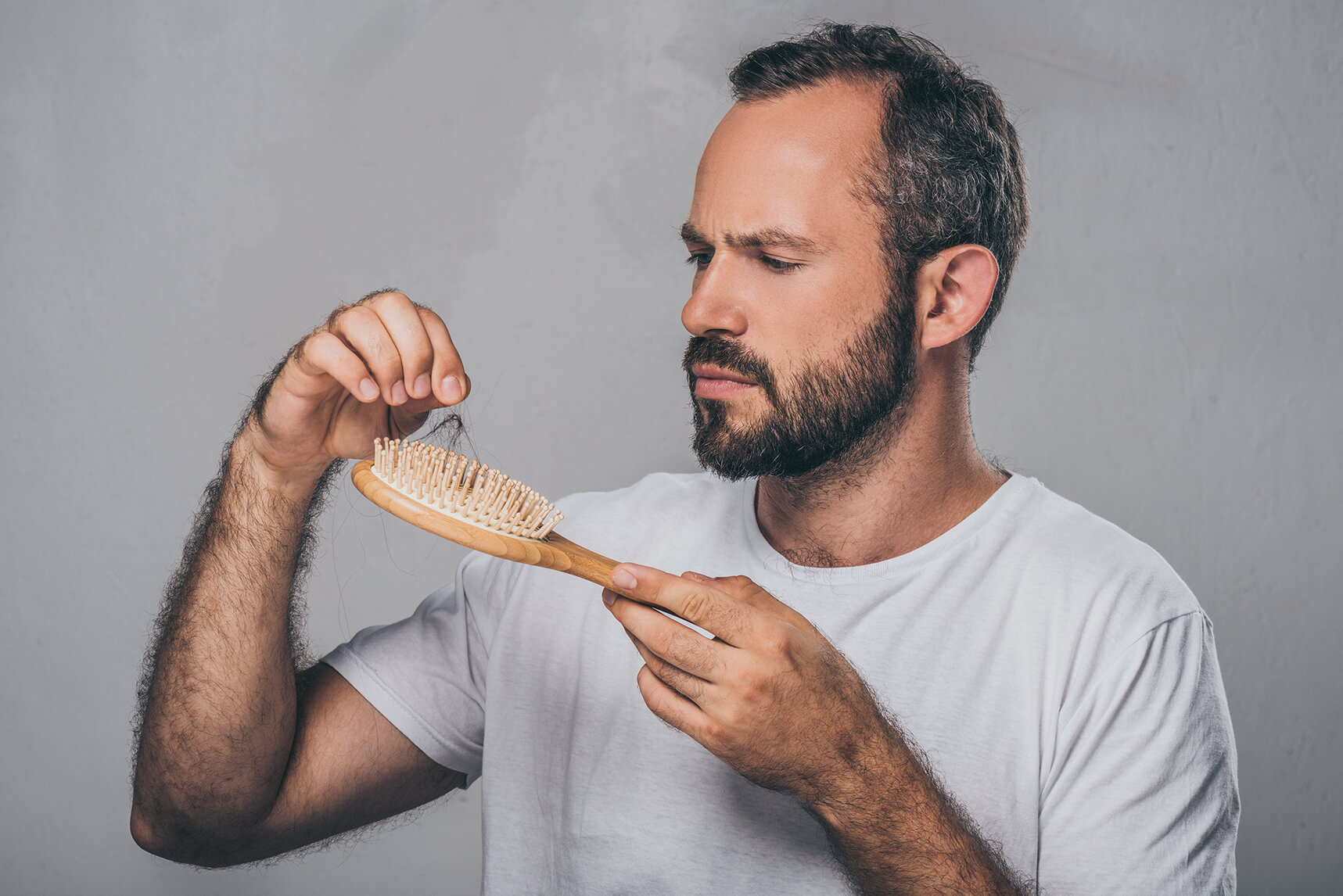 man inspecting hair left on a hairbrush