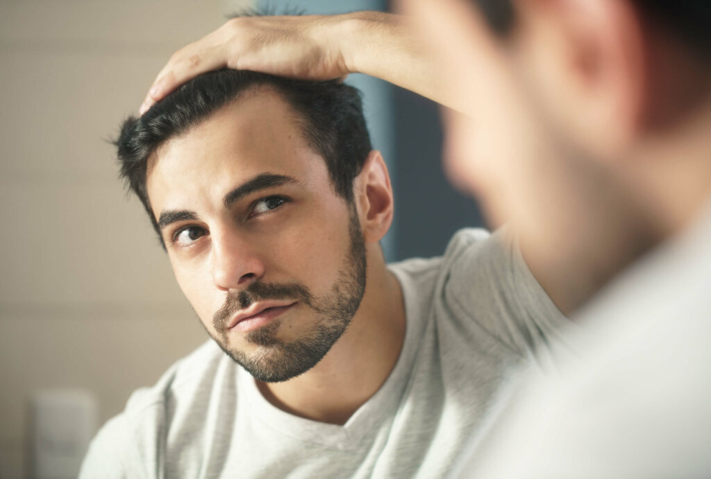 A close-up of a man inspecting his hairline in the mirror